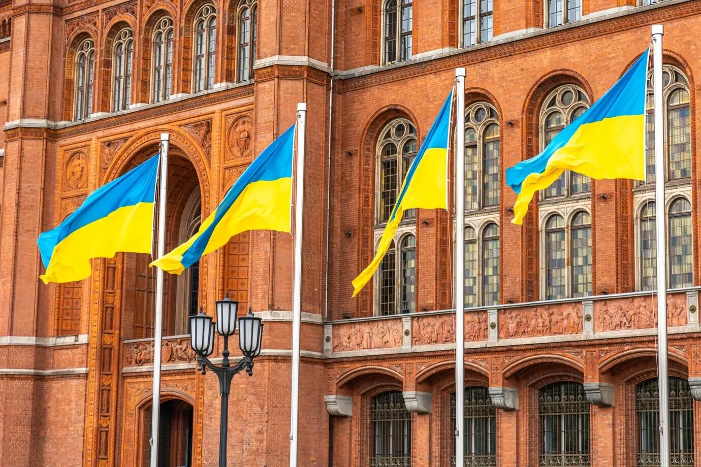 Ukrainische Flaggen wehen vor historischer Architektur, ein Symbol für Einheit und Würde.